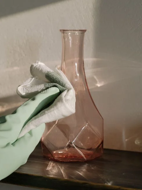 Femme en culture portant un sweat violet et des gants en latex, nettoyant un miroir dans un appartement lumineux en journée